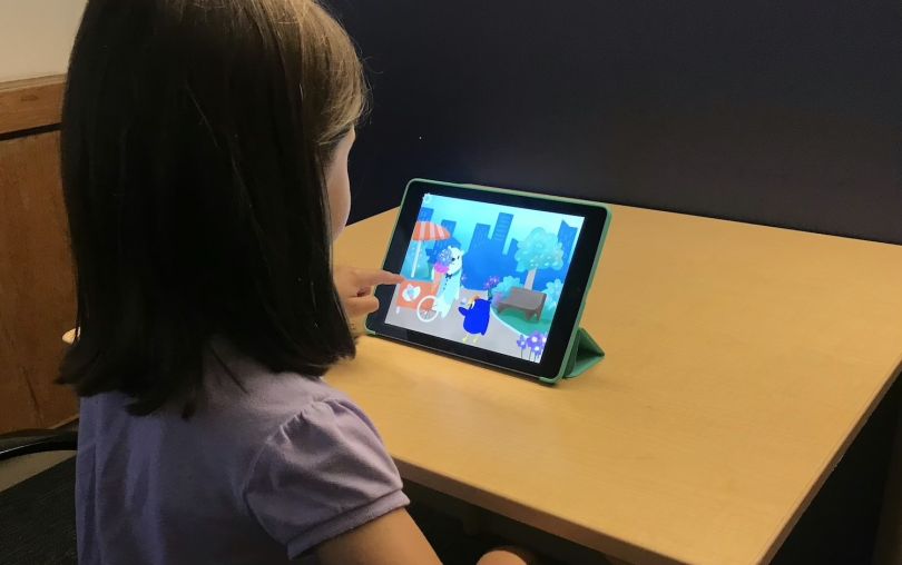 A girl plays EarlyBird Education's literacy assessment game on a tablet.