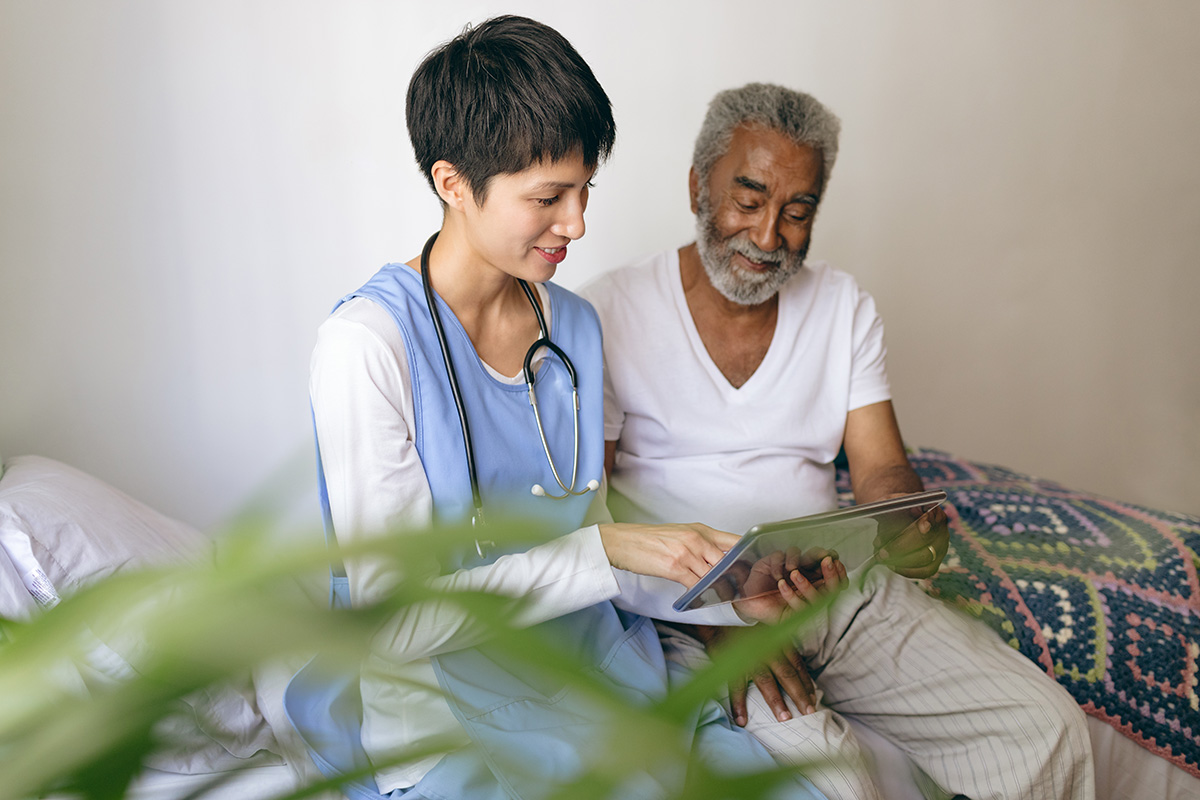 Female doctor and senior male patient using digital tablet at retirement home