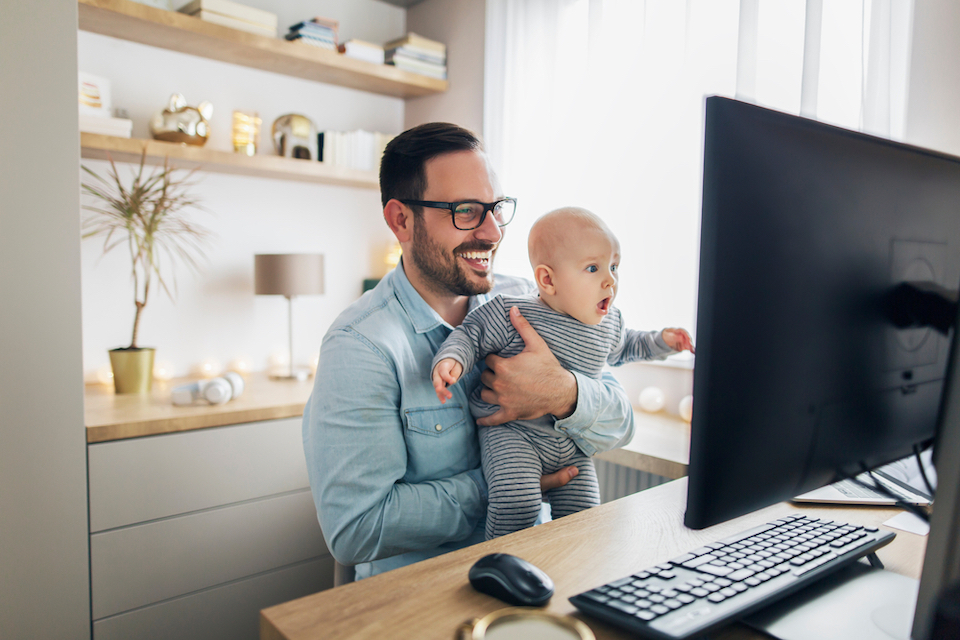 Dad working remote holding baby on conference call
