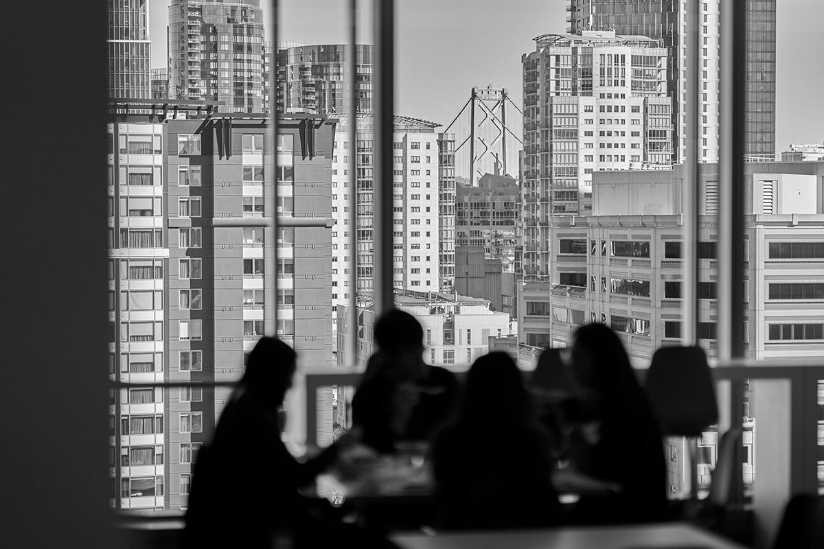 Black and white photo of blurred Benchling team members in the office with a view of the city out the window