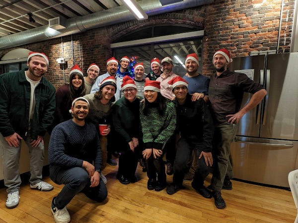 A group of Cohere Health employees wearing red Santa hats pose for a photo.
