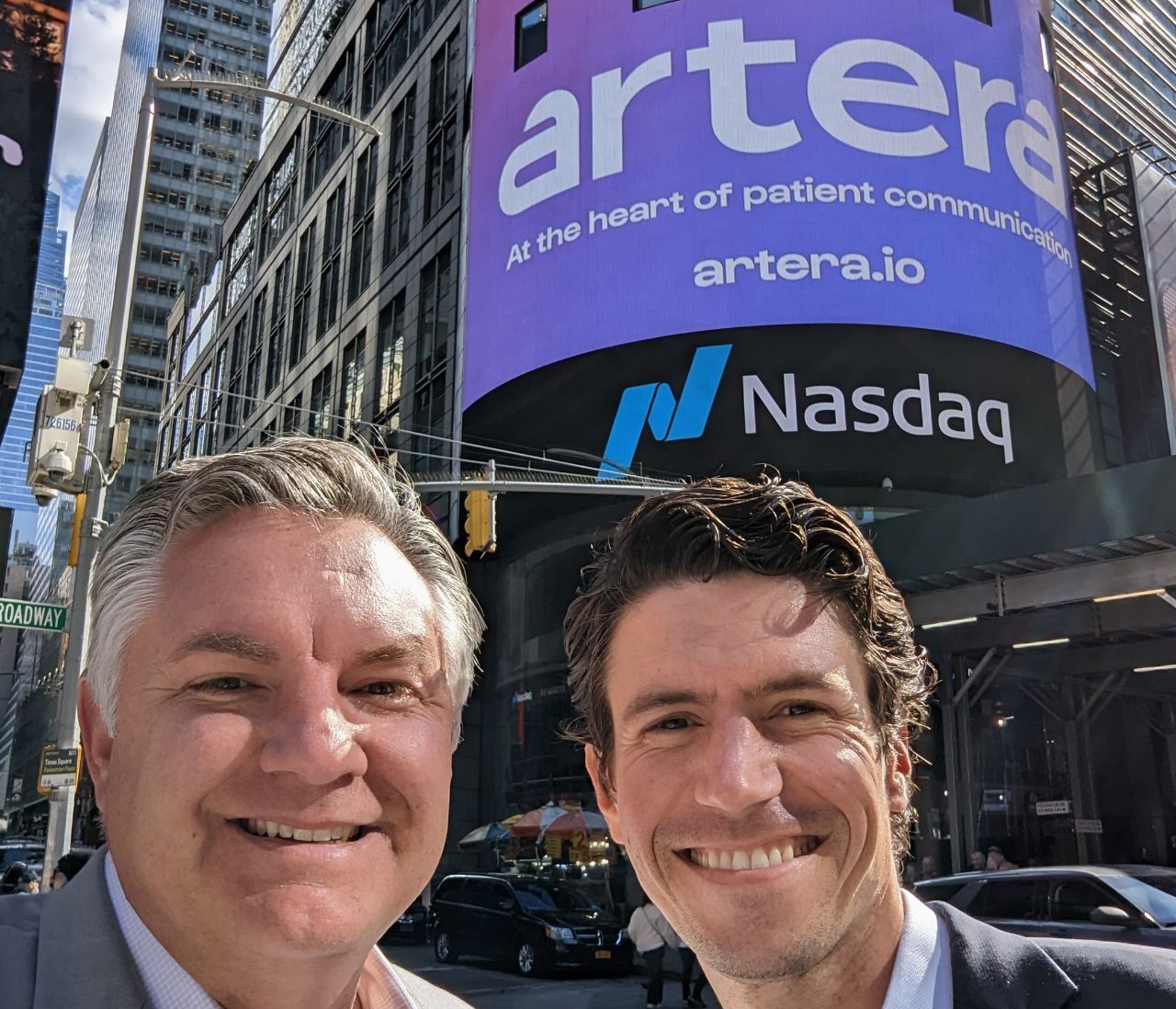 two men in front of NASDAQ digital board announcing artera rebrand