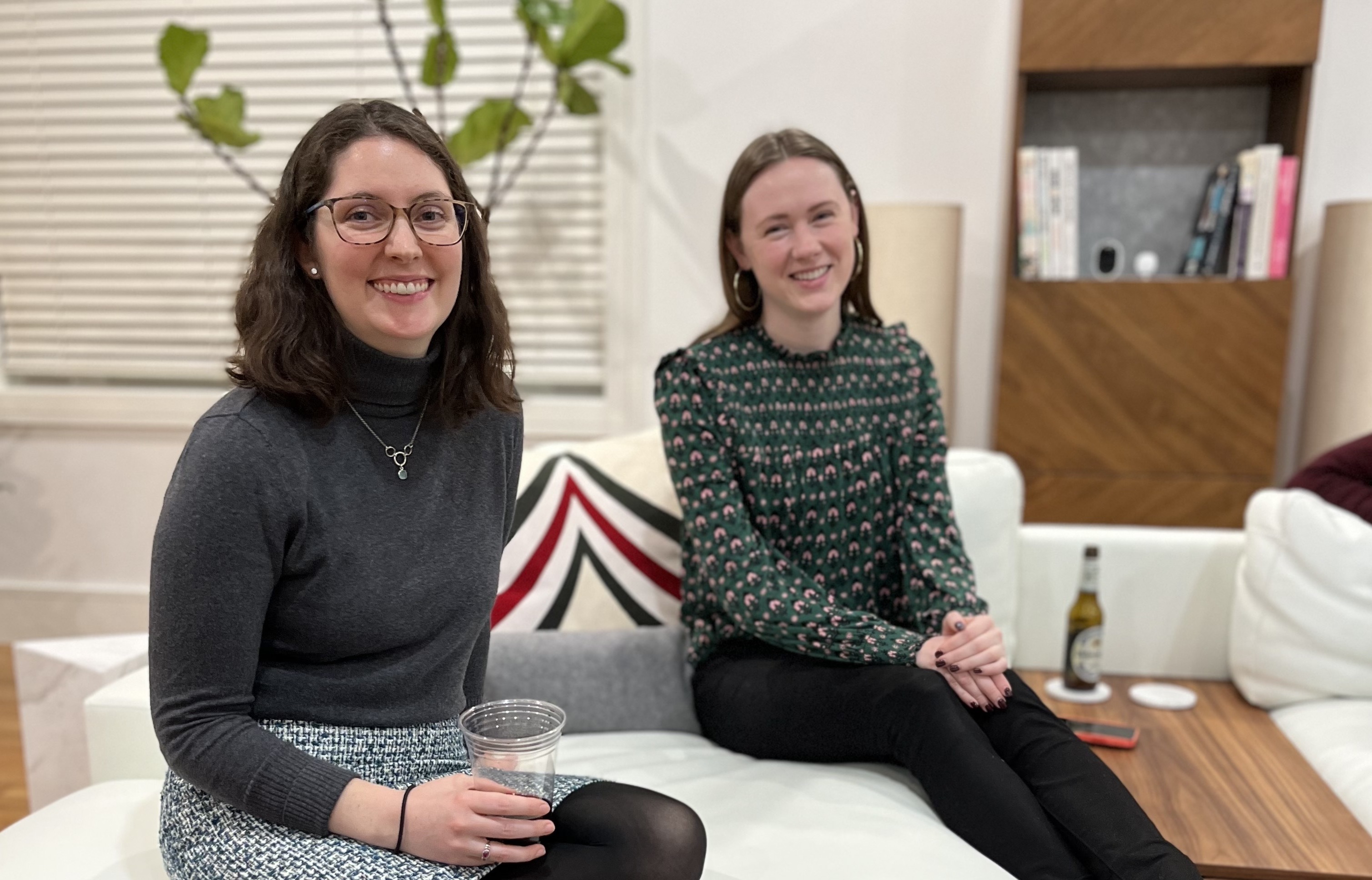 Two SmarterTravel team members sit on couch smiling.