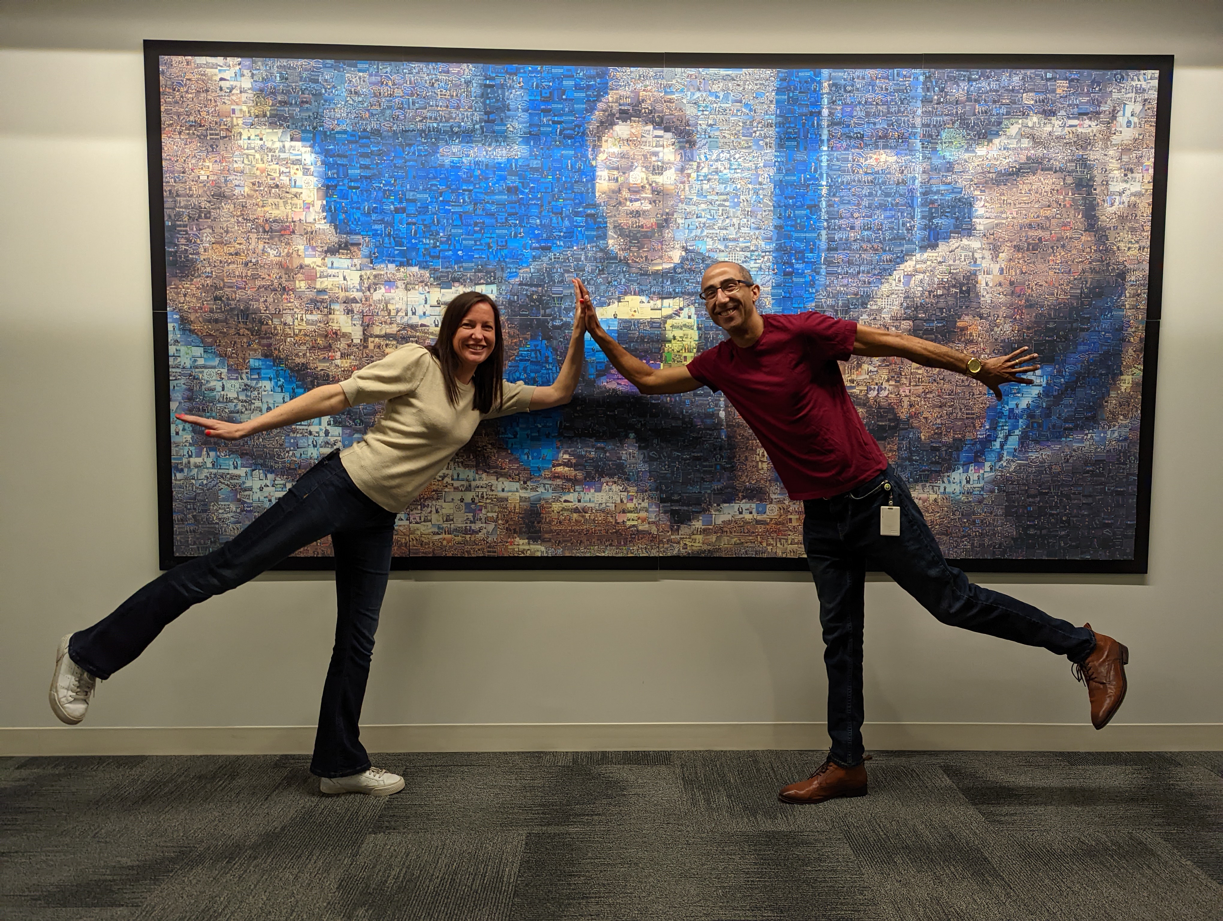  John Rocker and a colleague pose in a high-five position (each leaning forward on one foot) in front of a large wall-hung photo. 