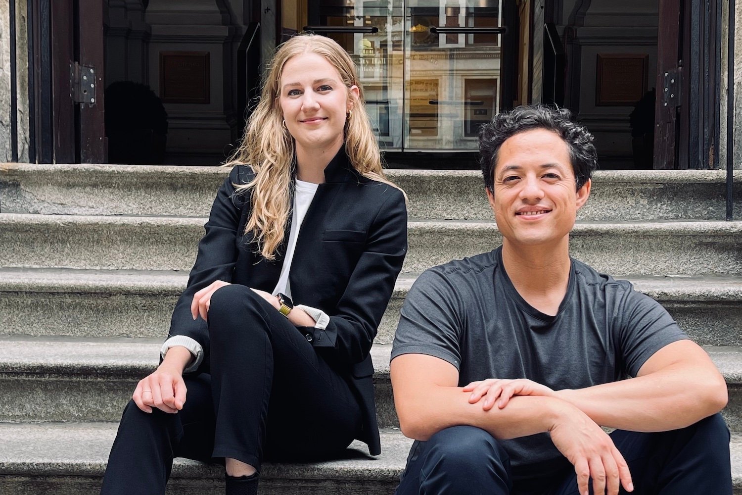 Perygee co-founders Mollie Breen, CEO, and Mark Watabe, CTO, sitting on the steps outside of a building.