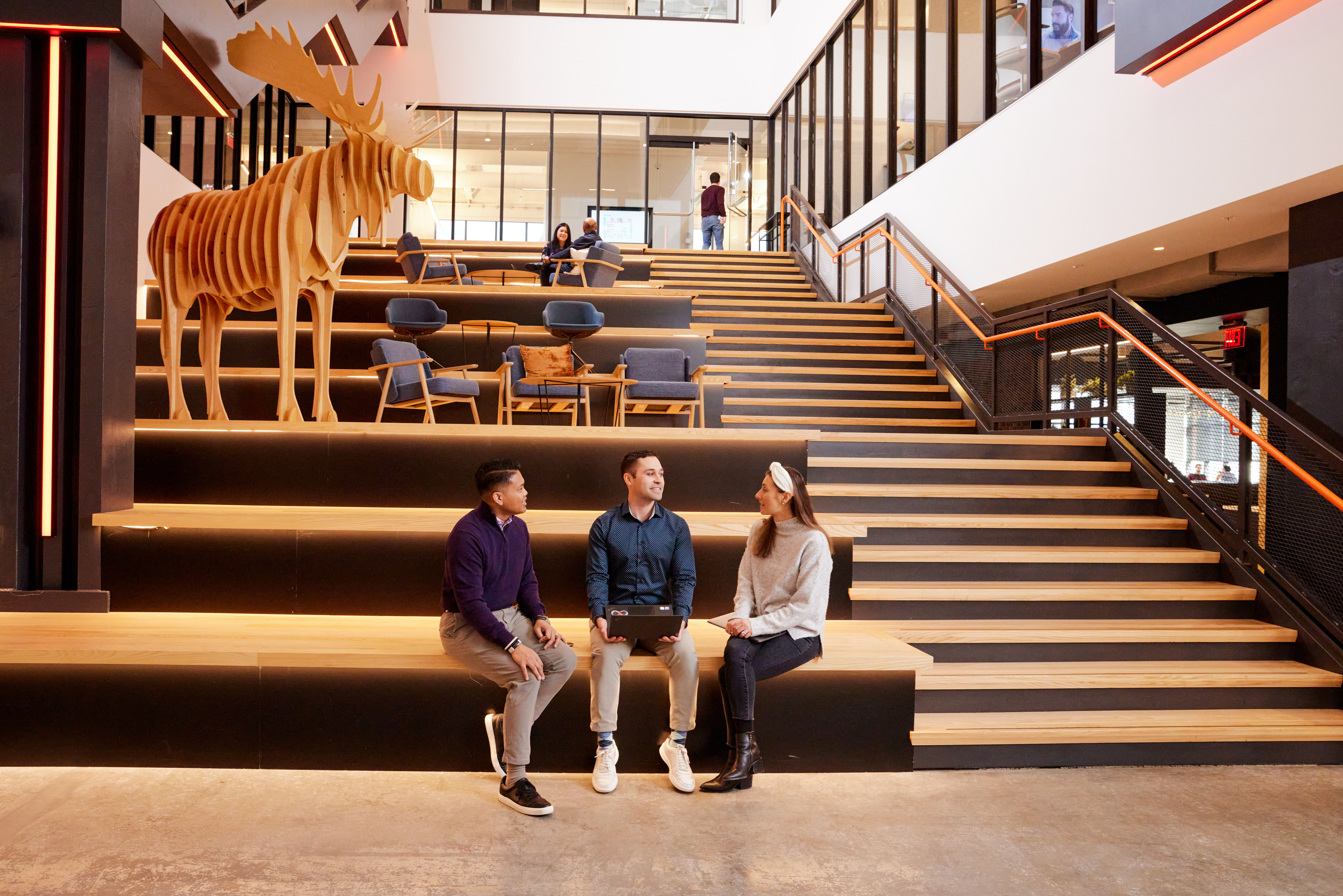 Three coworkers sit in a common area.