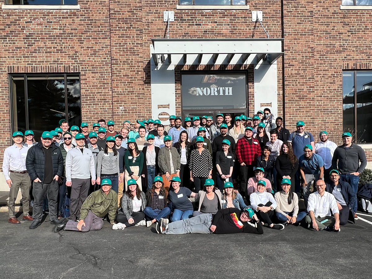 Zus Health group photo outside the office with team members wearing matching teal caps