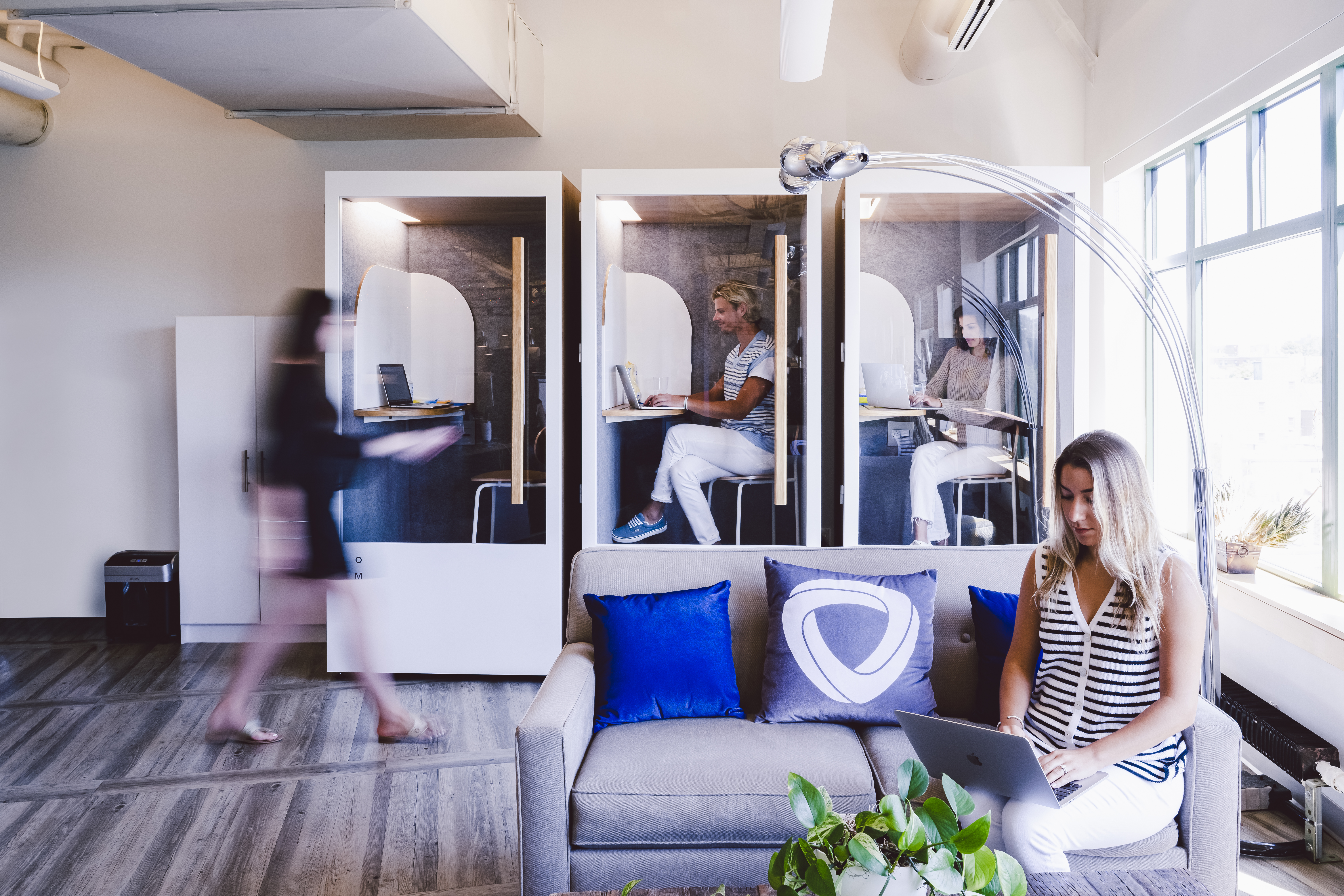 Mirakl team members in individual working “booths” in their office, with nearby lounge seating area. 