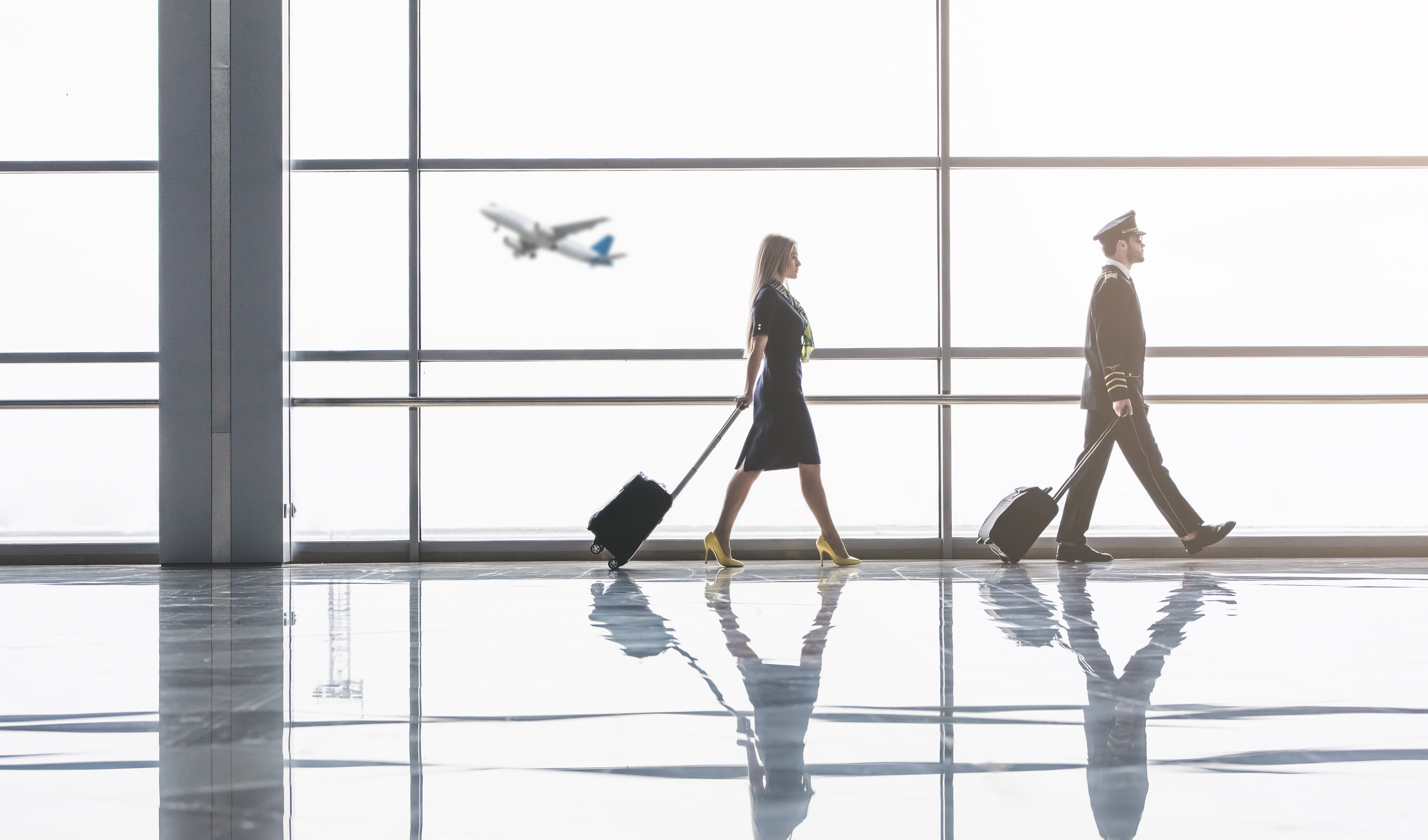 pilot and flight attendant walking next to big windows