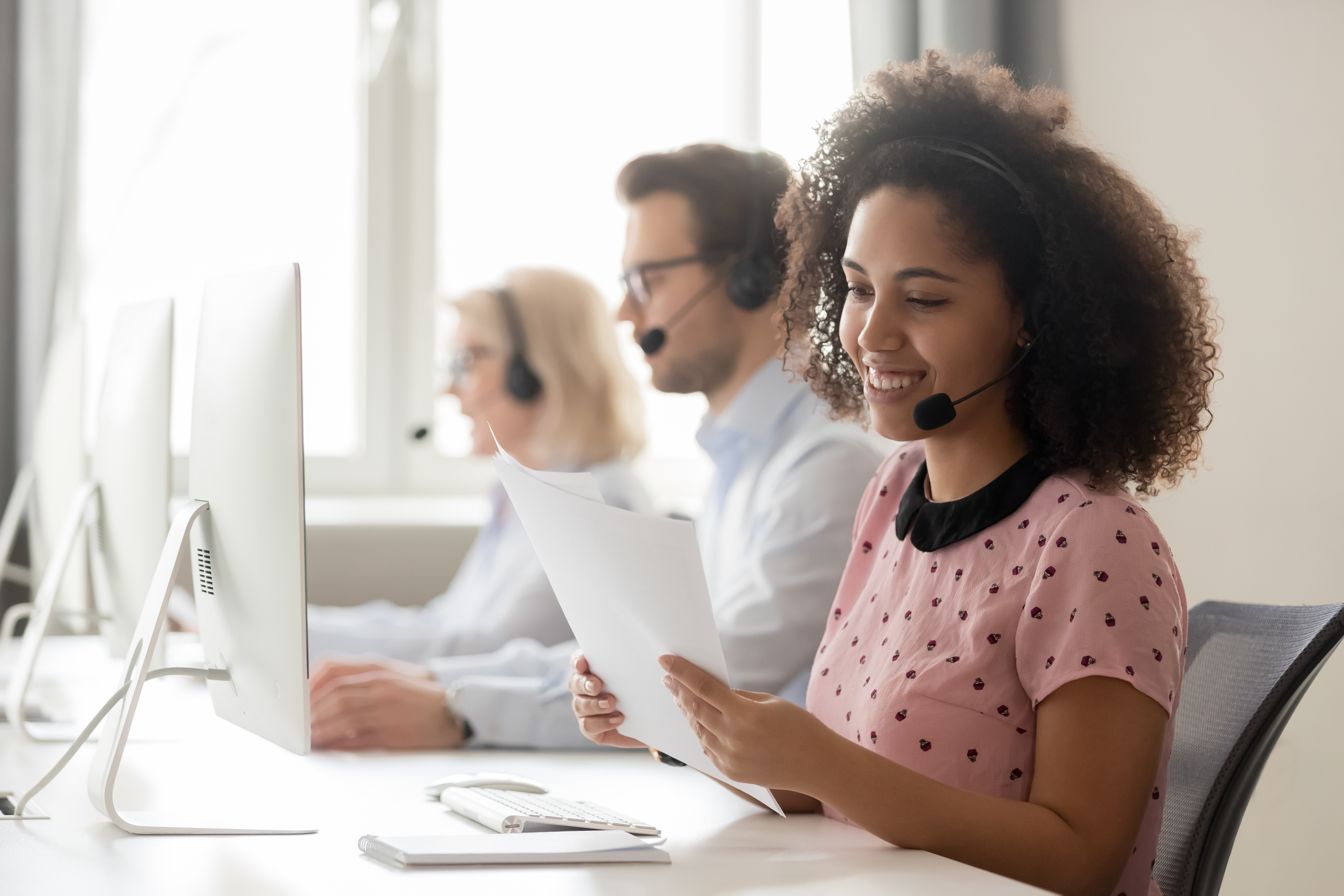 A team of tech sales professionals works side-by-side at a set of computers