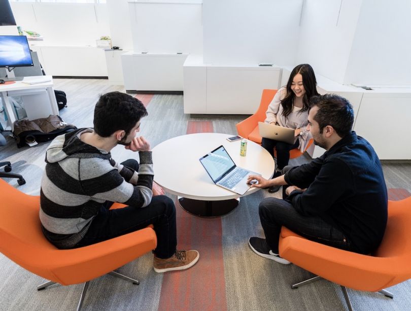 Veeva's office. Three employees sit around a table in comfortable-looking orange chairs.