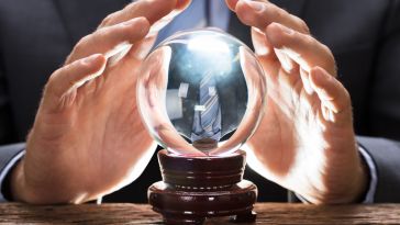A pair of hands hover over a crystal ball.