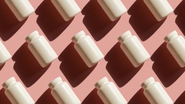 Stock photo of blank pill bottles against a pink background.