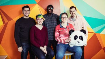 Wistia team members pose in front of a colorful wall with a panda bear head