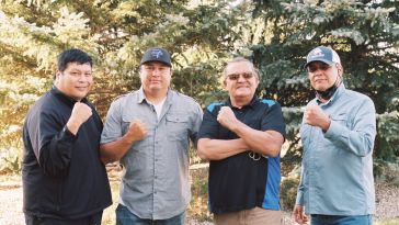 Indigenized Energy Initiative's team posing in front of evergreen trees.