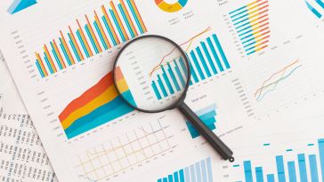 magnifying glass on top of papers with stats and graphs