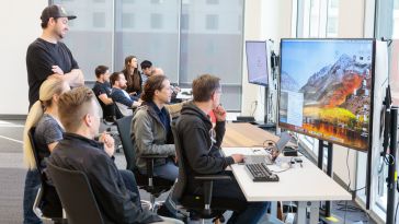 Pluralsight team members gather around a computer.