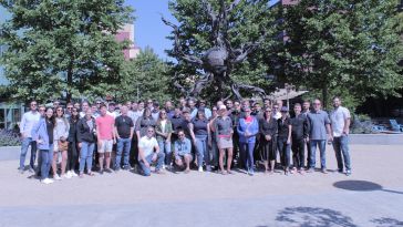 A large group of DIspatch employees pose together outside during a team outing.