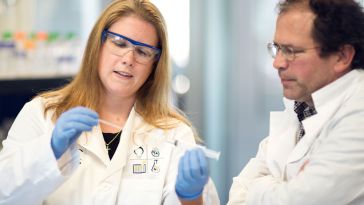 Lab Operations Manager Lindsay Poland (left) and Chief Scientific Officer Mitch Sanders (right) work in Alira Health’s lab in Framingham.