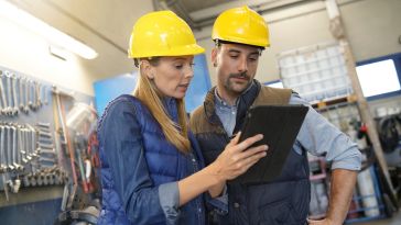 A manager provides instructions to employees using an electronic tablet.
