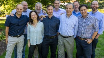 Ten people from Assured Allies’ management team pose for a group photo outside.