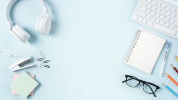 Photo of headphones, glasses, sticky notes, a notepad, and other supplies on a blue background