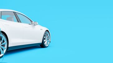 side view of white electric car charging against a bright blue backdrop