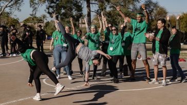 Group cheering, hands raised as two people cartwheel in front of them