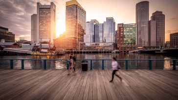 Downtown Boston at sunset with people walking in the foreground.