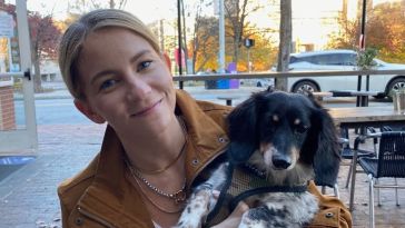 Photo of Morgan Simpson holding her dog at an outdoor cafe.