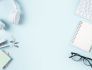 Photo of headphones, glasses, sticky notes, a notepad, and other supplies on a blue background