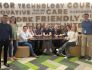 Group photo of Peapod Digital Labs team members sitting in a booth with stylized word wall behind them. 